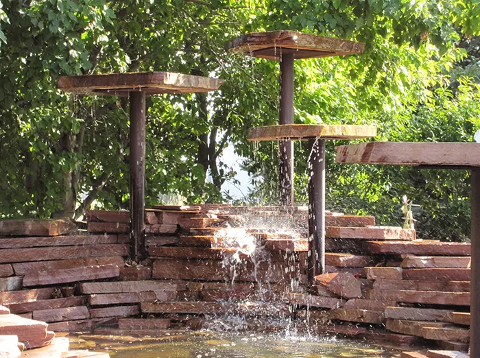 A fountain with wooden pillars and water coming out of it.